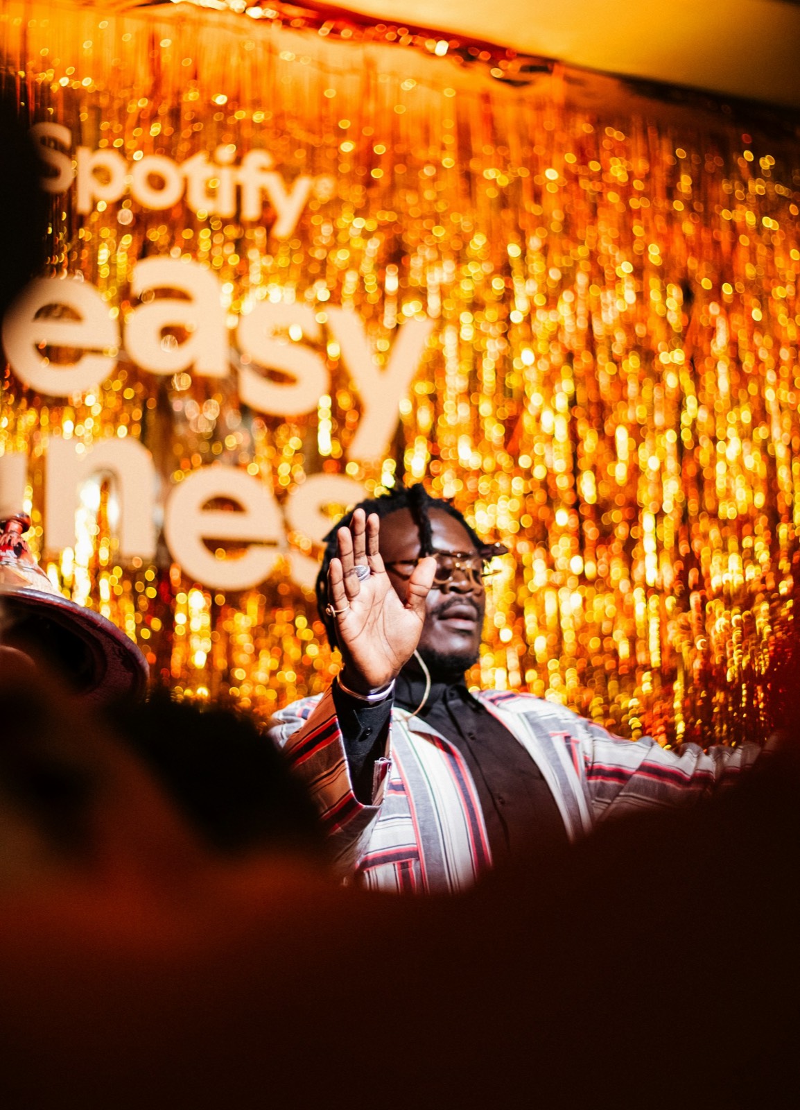 Performer with hands raised on a gold-lit stage